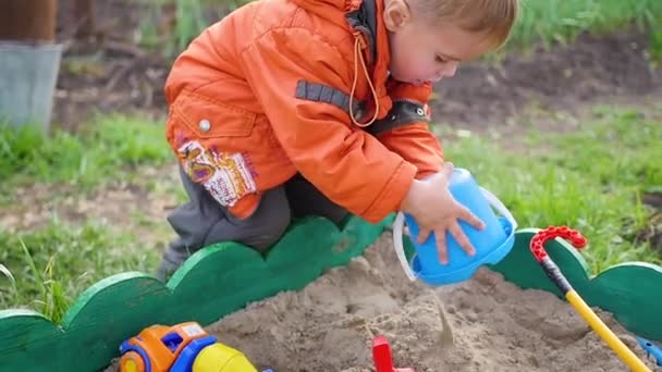 L'enfant joue avec les jouets dans le bac à sable. gros plan — Video