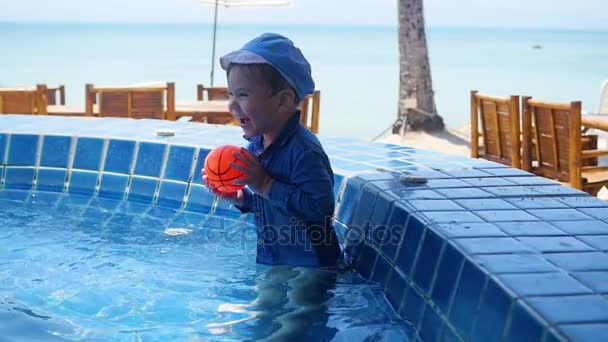 Малыш играет в мяч в бассейне. Спорт на открытом воздухе . — стоковое видео