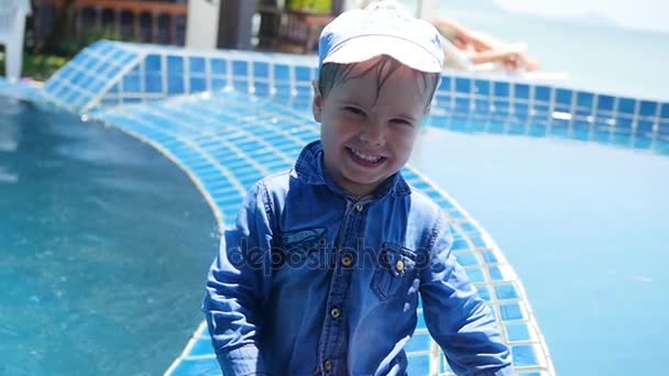 Un niño pequeño se sienta al lado de la piscina. Deportes al aire libre . — Vídeos de Stock
