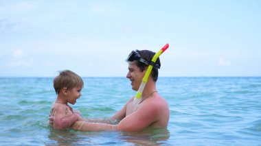 bir adam çocukla denizde eğleniyor çalış. Şnorkelle Dalma