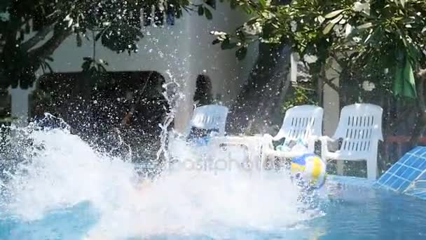 Kid hrát míč v bazénu. sportovní Outdoor. Skočit do bazénu s tryskající — Stock video