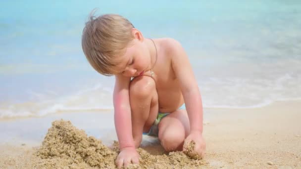 Gyermek játszik a homok a tengerparton a forró napsütésben — Stock videók