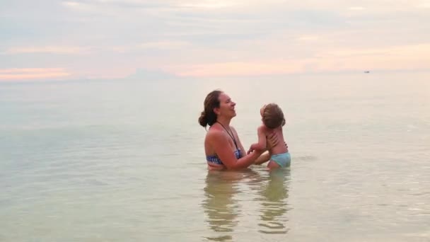 La fille et l'enfant nagent et jouent dans la mer. Heure du coucher du soleil — Video