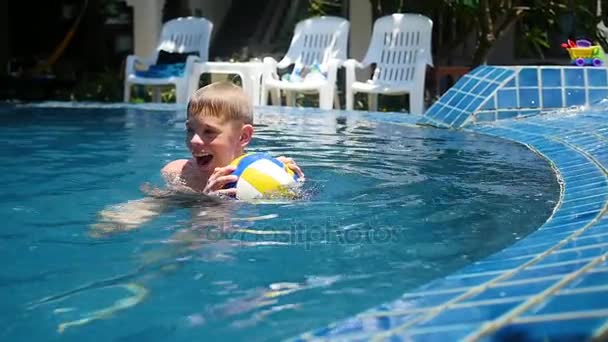 Ребёнок играет в мяч в бассейне. Спорт на открытом воздухе . — стоковое видео
