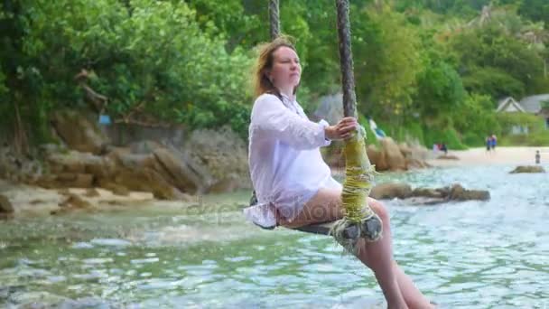 Ein Mädchen schaukelt auf einer Seilschaukel am Strand — Stockvideo