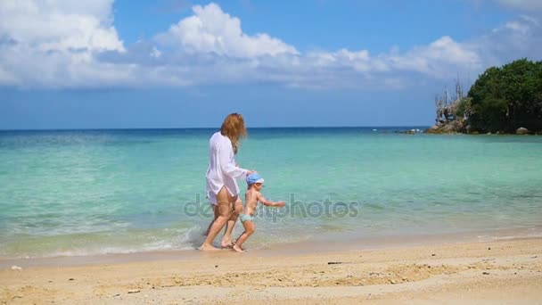 Chica con niño ir a pasear y jugar en la playa durante el día soleado — Vídeos de Stock