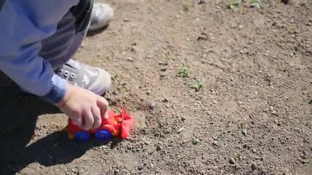 Uma criança está brincando com um carro de brinquedo na areia — Vídeo de Stock