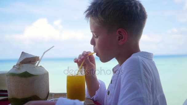 Mladý muž v kavárně pít koktejl na terase. venku. Kokosová voda — Stock video