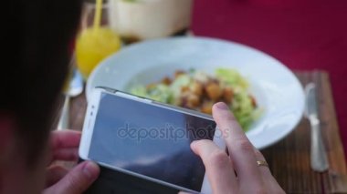 adam bir tabak yemek resmini alır. Bir anlık bir yemekle restoranda bir cep telefonu kamera ile fotoğraf çekin.