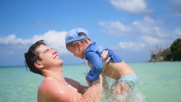 Un gars avec un enfant joue à s'amuser dans la mer . — Video