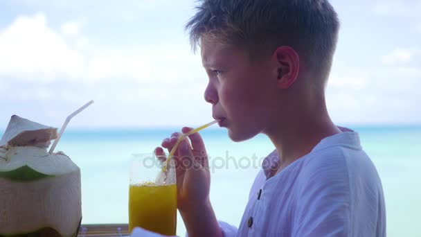 En ung man i ett café som dricka en cocktail på terrassen. utomhus. Kokosvatten — Stockvideo