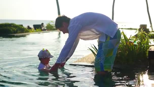 Ojciec z dzieckiem, zabawy w basenie obok plaży, zachód słońca. Tropikalna wyspa — Wideo stockowe