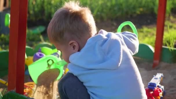 El niño juega con los juguetes en la caja de arena.Verano Día soleado — Vídeo de stock