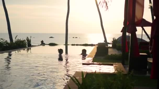 Sahilde güzel restoran. Romantik bir yer için aşık. Bir adam ve bir kız havuzda yüzüyor. Günbatımı — Stok video