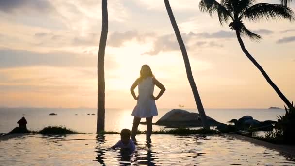 Девочка с ребенком гуляет и играет на пляже во время заката. семейный отдых — стоковое видео