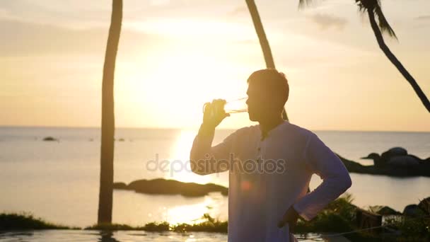 Le gars assis sur la plage et boire de la bière. — Video