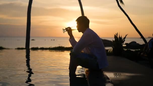 De man zit op het strand en drinken bier. Zonsondergang tijd — Stockvideo