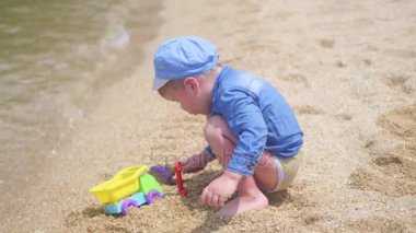 Bir çocuk kum ve oyuncaklar ile sahilde sıcak güneşli bir günde çalış