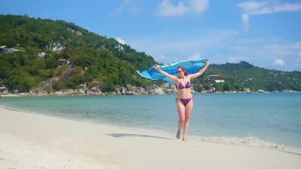 Une jeune fille avec un paréo est le long du rivage de la plage. Île tropicale, le vent chaud de l'été — Video