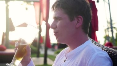 Adam açık restoranda oturan ve bira içmek. Günbatımı Zamanı