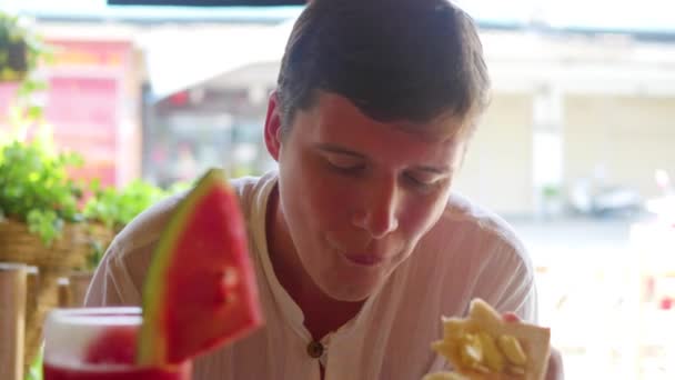 Genç adam sokak bir kafede yemek yiyor. Açık havada. Asya Mutfağı — Stok video