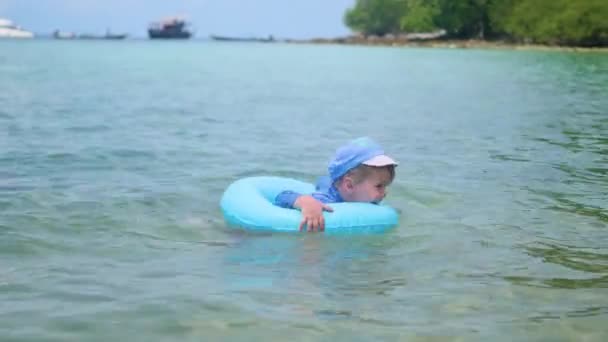 Un niño feliz nada en un círculo inflable en el mar — Vídeo de stock