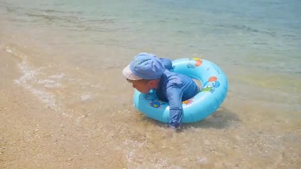 Ein glückliches Kind schwimmt in einem aufblasbaren Kreis im Meer — Stockvideo