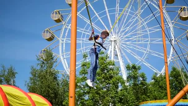 Gyermeke kipróbálhassa a szórakoztató: egy szórakoztató Park.Jumping-a a következő Trambulin — Stock videók