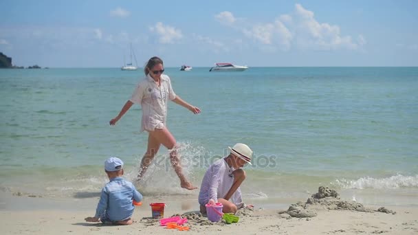 Lycklig familj med barn och hund spelar på sandstranden med leksaker. Tropisk ö, en varm dag — Stockvideo