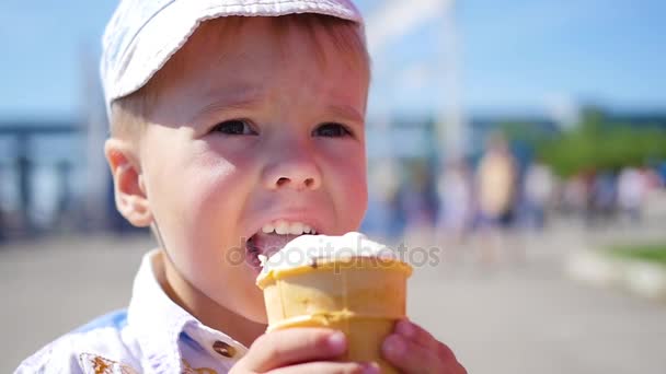 El niño come una taza de helado de gofre en el parque en primer plano — Vídeos de Stock