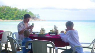 Çocuklu bir aile sahilde bir restoranda akşam. Gıda açık havada
