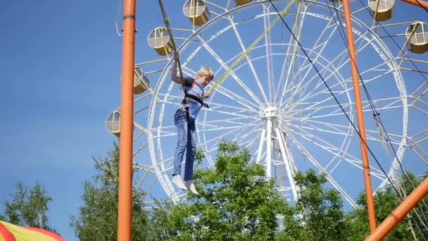Criança se divertindo em um parque de diversões. Saltando em um trampolim. Férias em família no parque — Vídeo de Stock