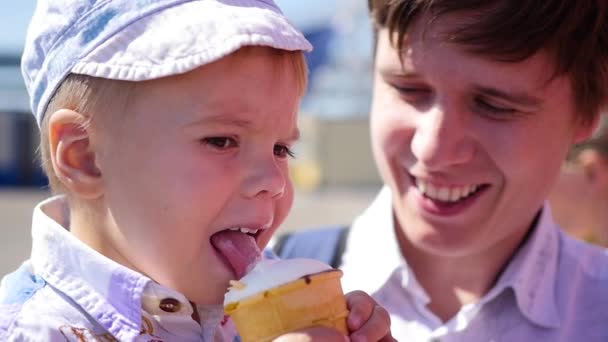 A criança come um sorvete de xícara de waffle no parque no close-up. Férias em família no parque — Vídeo de Stock