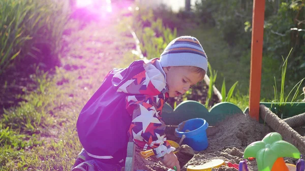 Το παιδί παίζει με τα παιχνίδια στο sandbox. Ηλιόλουστη μέρα του καλοκαιριού. Διασκέδαση και παιχνίδια σε εξωτερικούς χώρους — Φωτογραφία Αρχείου
