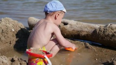 Bir çocuk kum ve oyuncaklar ile sahilde sıcak güneşli bir günde çalış. Eğlence ve açık hava oyunları