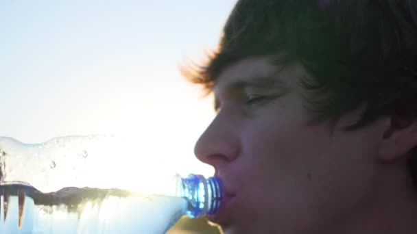 Ragazzo beve acqua dalla bottiglia al tramonto — Video Stock