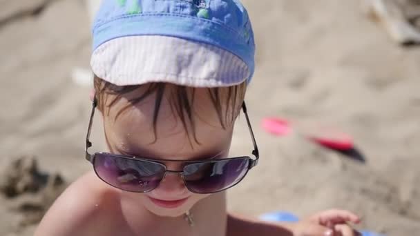 Het kind probeert te dragen zonnebril. Het strand, een zonnige warme dag — Stockvideo