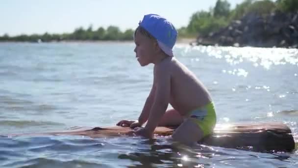 एक खुश बच्चे समुद्र में तैरता है। मज़ा और खेल आउटडोर — स्टॉक वीडियो