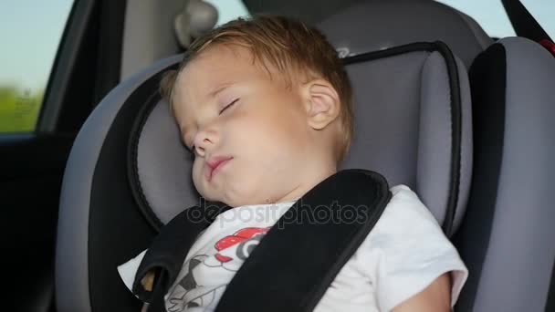 The baby sleeps in the car in the way. Sleeping child at back chair in car in slow motion. — Stock Video