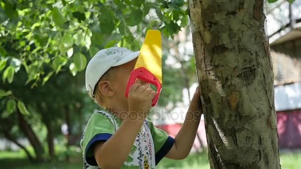 Дитина стоячи у парку біля дерева. Рухливі Ігри — стокове відео
