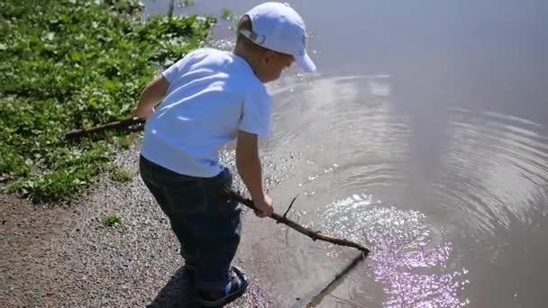 Un niño jugando cerca del estanque. juegos al aire libre — Vídeos de Stock