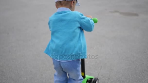 Щаслива дитина їде скутері в Park.Fun на відкритому повітрі. Розмиття — стокове відео