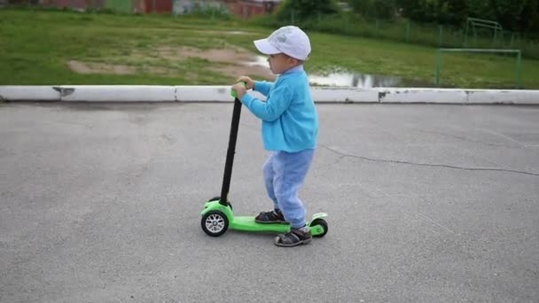 Ein glückliches Kind fährt mit seinem Roller im Park.Spaß im Freien — Stockvideo