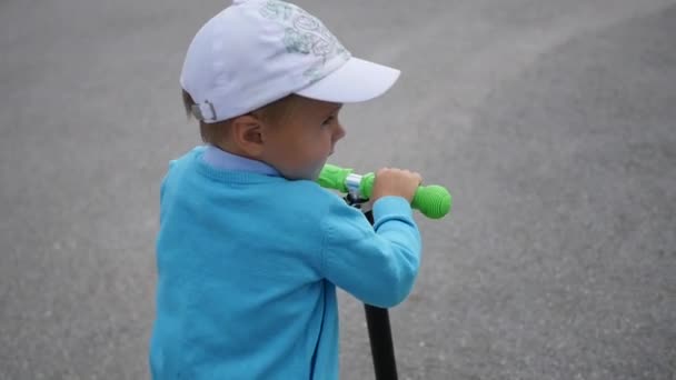 Ein glückliches Kind fährt mit seinem Roller im Park.Spaß im Freien — Stockvideo
