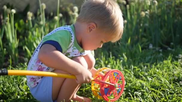 Un niño está jugando con un juguete en el césped. Juegos de entretenimiento y al aire libre — Vídeos de Stock