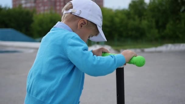 Ένα χαρούμενο παιδί βόλτες με σκούτερ του σε εξωτερικούς χώρους Park.Fun — Αρχείο Βίντεο