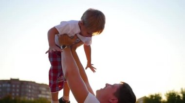 Ağır çekim. genç bir baba havada onun gülen bebek kusuyor. Açık Rekreasyon
