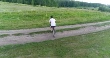 bir ülke yolda bisiklet sürme bir çocuk olan genç bir adam. Bir dron--dan ateş. Spor açık havada