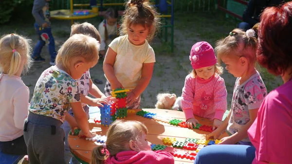 NOVOSIBIRSK, RUSSIA - 16 Agustus 2017: Di taman kanak-kanak, wanita yang bermain dengan anak-anak, permainan aktif di luar ruangan. lembaga pendidikan prasekolah Stok Foto