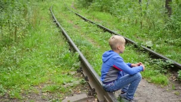 Un adolescente solitario seduto su binari ferroviari — Video Stock